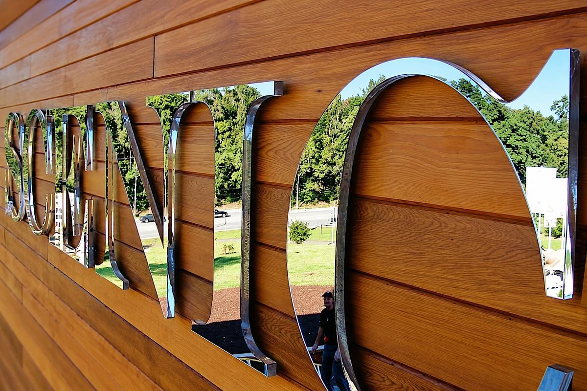 SCENIC second-surface mirror letters reflecting surrounding landscape on a warm wood sales-office facade in Toronto