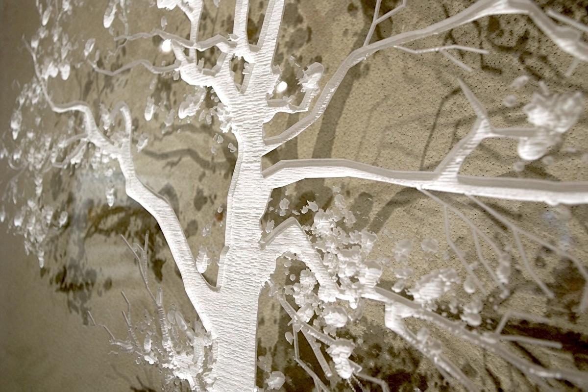 Angled close-up of raster-engraved tree branches in a clear acrylic office sign