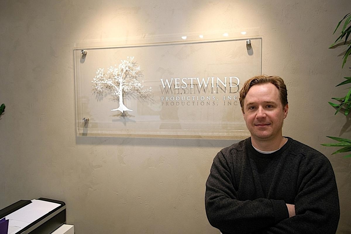 Rob Sockett beside a clear acrylic Westwind Productions office sign in Toronto