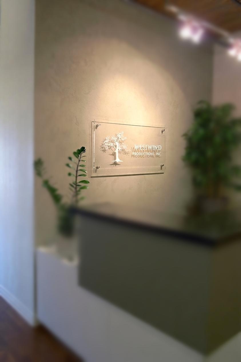 Wide Toronto reception view of a clear acrylic Westwind lobby sign under spot lighting