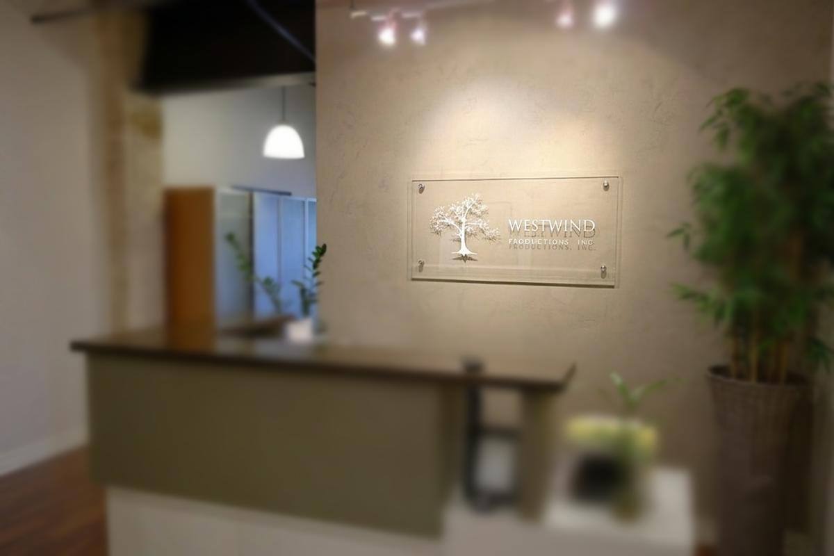 Clear acrylic Westwind Associates lobby sign with engraved tree behind a Toronto reception desk